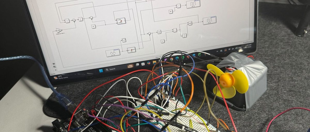 The thermal digital twin rig on a desk with the Simulink model open on the monitor behind it